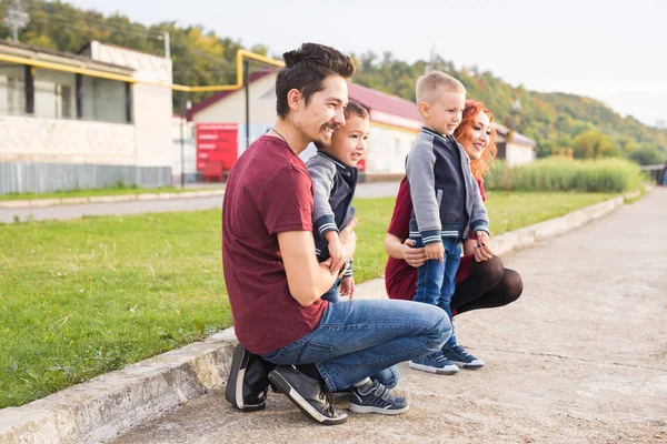 Elternschaft, Kindheit und Familienkonzept - Eltern und zwei männliche Kinder gehen durch den Park und schauen sich etwas an — Stockfoto