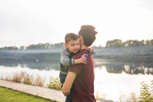 Concepto de paternidad e hijos - Padre sosteniendo a su pequeño hijo en la naturaleza — Foto de Stock