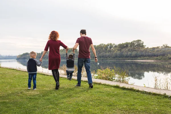 Parent, childhood and nature concept - Family playing with two sons by the water — Stock Photo, Image