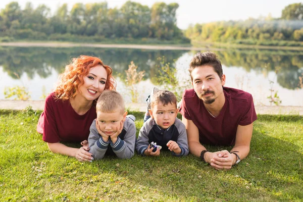 Concepto de la infancia y la naturaleza - Familia con hijos pequeños sentados en la hierba verde — Foto de Stock