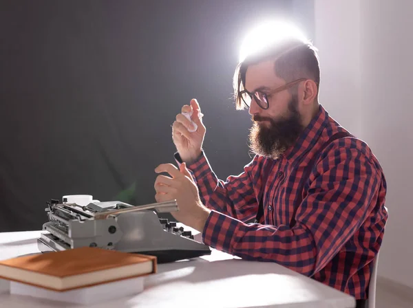 Gente y concepto de tecnología - Día Mundial del escritor, hombre guapo con barba trabajando en la máquina de escribir sobre fondo negro — Foto de Stock