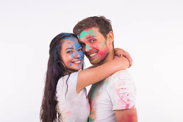 Conceito de férias, holi e pessoas - Sorrindo mulher engraçada e homem posando com pó multicolorido em seus rostos no fundo branco — Fotografia de Stock