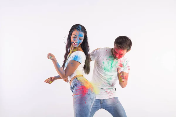 Conceito de férias, holi e pessoas - Casal feliz se divertindo com pó multicolorido em seus rostos no fundo branco — Fotografia de Stock