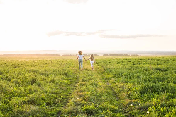 家庭、夏季和节日概念--母亲牵着女儿的手在绿地上奔跑 — 图库照片