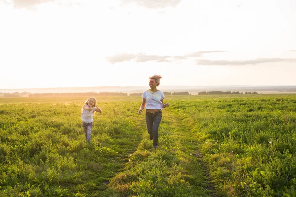 Familj, sommar och semester koncept - lilla dotter och mor kör i fältet sommaren — Stockfoto