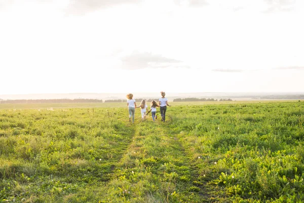 Koncepcja rodziny, lato i wakacje - grupa kobiet i dziewcząt, odchodzi w zielone pola — Zdjęcie stockowe