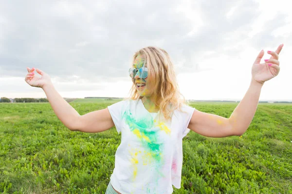 Eğlenceli, holi Festivali ve tatil kavramı - komik kadın doğa arka plan üzerinde gülümseyen renk toz kaplı
