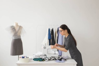 Terzi, moda tasarımcısı ve terzi kavramı - giysi raf elbise arka plan ile genç terzi kadın