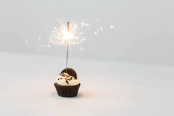 Cibo e concetto di vacanza - Cupcake di compleanno con sparkler su sfondo bianco con spazio copia — Foto Stock