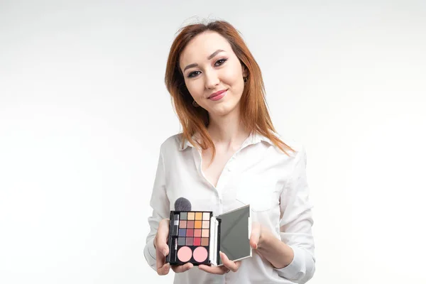 Attraktive Visagistin oder koreanische Visagistin mit einem Make-up-Pinsel und einer Palette von Lidschatten auf weißem Hintergrund — Stockfoto