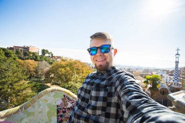 Seyahat ve tatil kavramı - yakışıklı adam akıllı telefon Park Guell, Barselona, İspanya, gülümseyen ile kamera çekimi fotoğrafa bakan.
