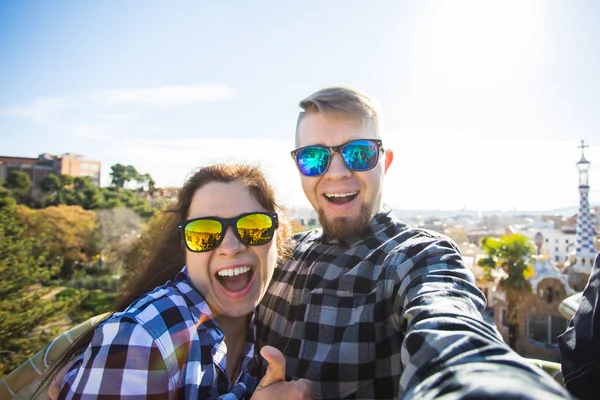 Komik genç çift kamera ile akıllı telefon Park Guell, Barselona, İspanya, gülümseyen fotoğrafı çekmek. — Stok fotoğraf
