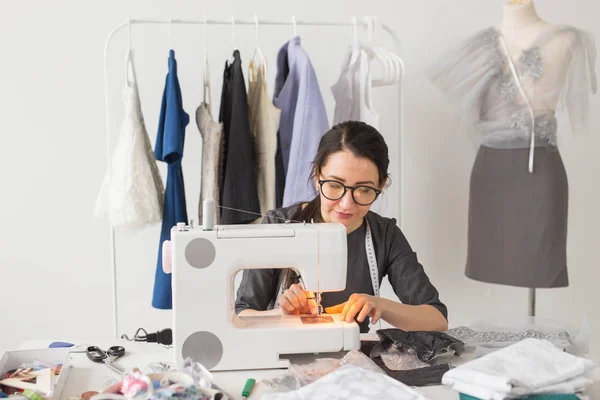 Les gens et le concept de mode - Jeune couturière femme coud des vêtements sur la machine à coudre — Photo