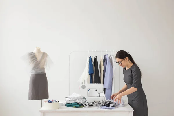 People and fashion concept - Young dressmaker woman sews clothes on sewing machine — Stock Photo, Image