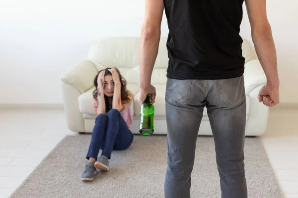 Domestic violence, alcoholic and abuse concept - drunk man with bottle abusing his wife lying on the floor — Stock Photo, Image