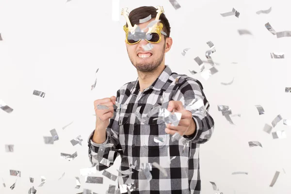 Люди, свята та концепція вечірки - смішний хлопець в окулярах танцює в конфетті на білому тлі — стокове фото