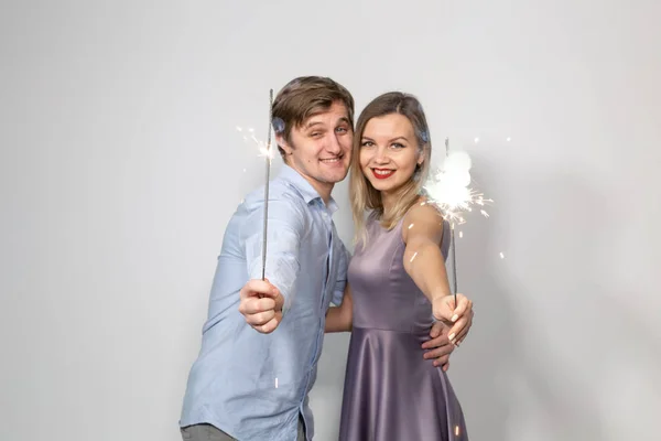 Conceito de feriados, festas e celebrações - jovem casal com brilhos no fundo branco — Fotografia de Stock