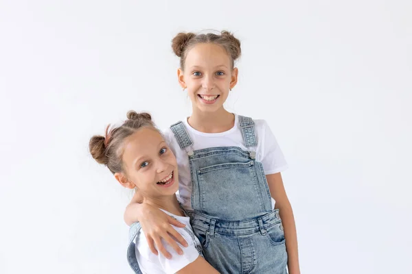 Concepto de familia y amor: dos hermanas gemelas sonrientes abrazándose sobre un fondo blanco — Foto de Stock