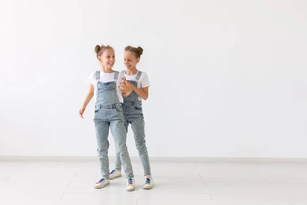 Concepto de familia y amor: dos hermanas gemelas sonrientes que se divierten sobre fondo blanco con espacio para copiar — Foto de Stock