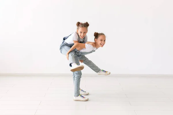 Conceito de família e amor - menina gêmea feliz dando passeio de piggyback para sua irmã rindo — Fotografia de Stock