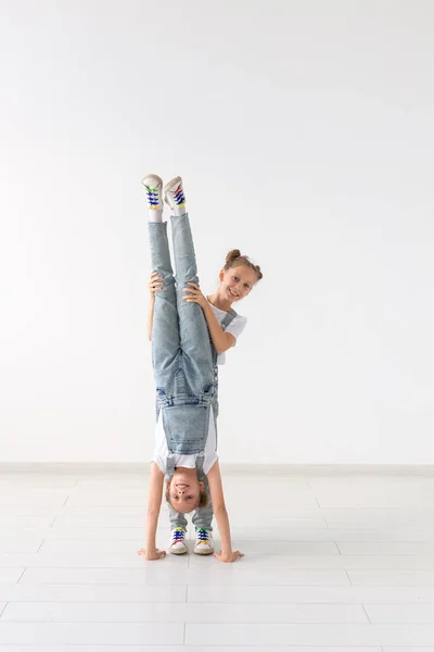 Concetto di famiglia e sport - Due acrobati gemelle sono in piedi sulle mani su sfondo bianco — Foto Stock