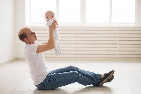 Concepto de familia, paternidad e hijos - padre calvo sosteniendo lindo recién nacido en casa — Foto de Stock
