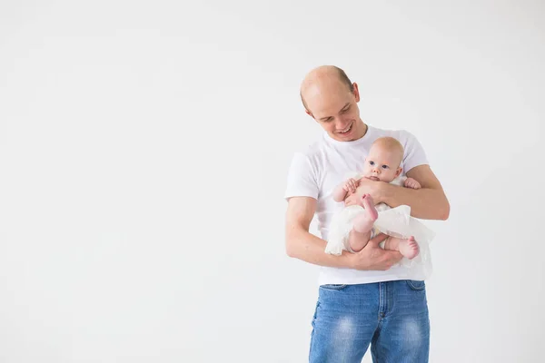 Concepto de paternidad, familia y paternidad: padre calvo abrazando a su pequeña hija bebé sobre un fondo blanco con espacio para copiar — Foto de Stock