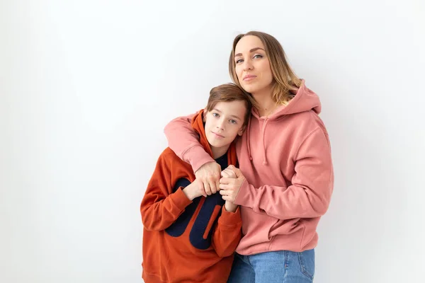 Fête des mères, concept des enfants et de la famille - adolescent garçon étreignant sa mère sur fond blanc — Photo