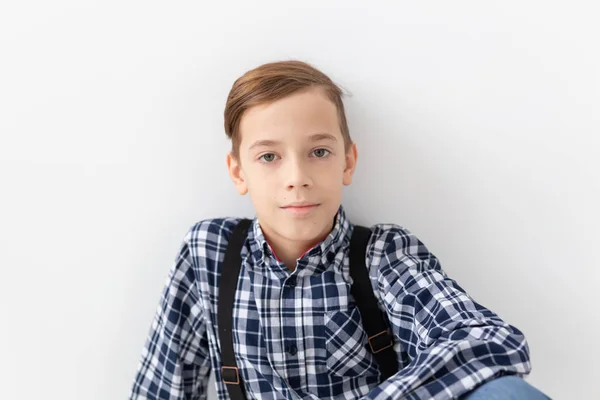 Tiener, kinderen en fashion concept - portret van jongen gekleed in plaid shirt poseren op witte achtergrond — Stockfoto