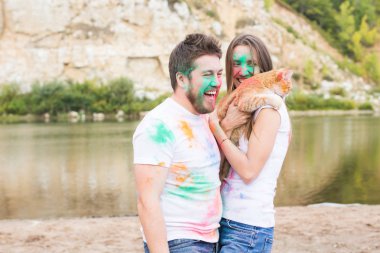 Evde beslenen hayvan, yaz turizm, festival holi ve doğa kavramı - komik erkek ve kadın ile kedi doğal zemin üzerine