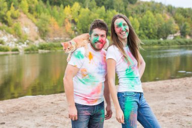 Evde beslenen hayvan, yaz turizm, festival holi ve doğa kavramı - komik erkek ve kadın ile kedi doğal zemin üzerine