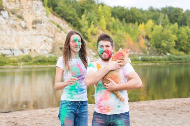 Evde beslenen hayvan, yaz turizm, festival holi ve doğa kavramı - komik erkek ve kadın ile kedi doğal zemin üzerine