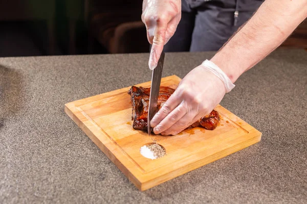 Еда, вкусная и ремесленная концепция - Человек режет мясо лошади стейк — стоковое фото