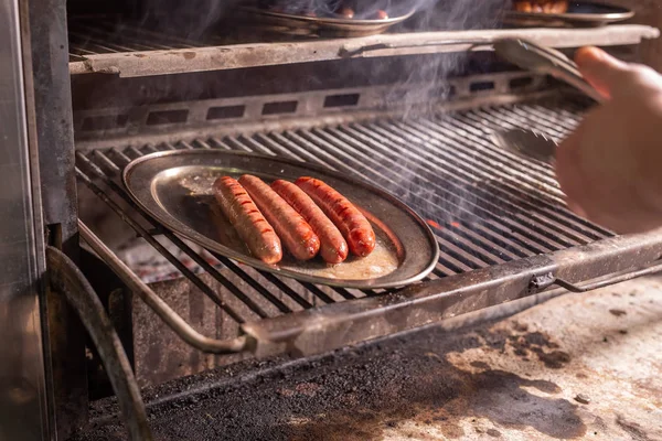 Comida, artesanía y delicioso concepto - salchichas de cocina en una parrilla — Foto de Stock