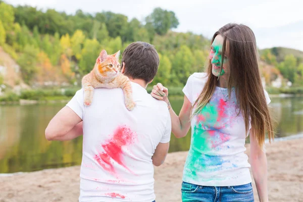 축제 holi, 관광 및 자연 개념-여자와 고양이 함께 남자의 초상화 덮여 멀티 컬러 먼지 — 스톡 사진