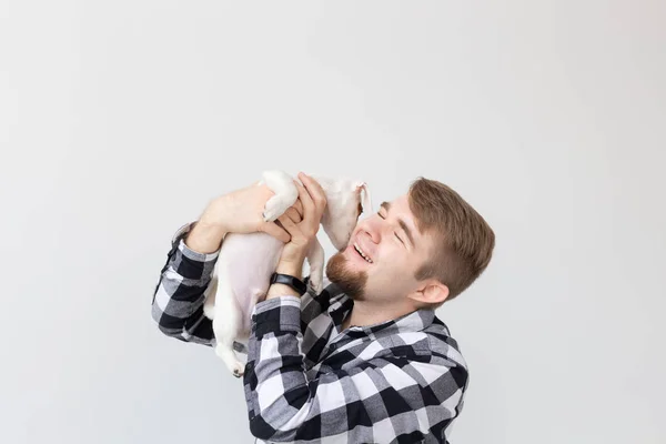 Conceito de pessoas, animais de estimação e animais - jovem segurando Jack Russell terrier filhote de cachorro no fundo branco — Fotografia de Stock