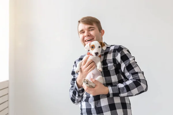 Pessoas, pet and dog concept - Homem sorridente sobre fundo branco segurando cachorro Jack Russell Terrier — Fotografia de Stock