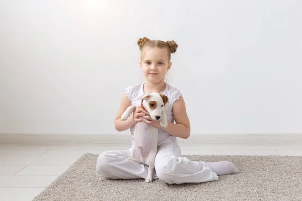 Concepto de personas, niños y mascotas - niña pequeña acostada en el suelo con un lindo cachorro Jack Russell Terrier — Foto de Stock