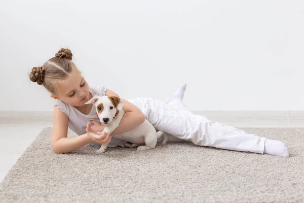 Concepto de la infancia, mascotas y perros - Niña posando en el suelo con el cachorro — Foto de Stock