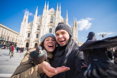 Seyahat ve tatil kavramı - Milano Duomo Katedrali önünde komik güvercinler ile kendi kendine portre alarak mutlu turistler kış