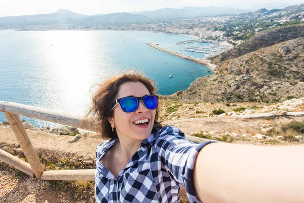 Подорожі, туризм та концепція відпустки Щаслива молода жінка бере селфі біля моря — стокове фото