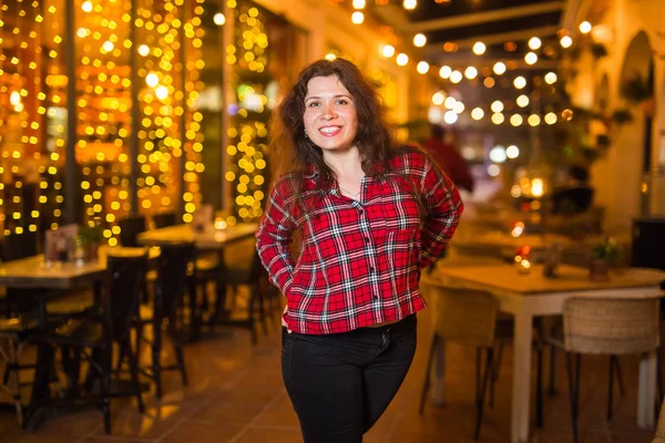 Mulher bonita em uma camisa vermelha em um fundo de uma cidade noturna — Fotografia de Stock