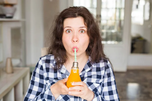 Health, food, diet and people concept - young woman drinking natural juice in a bottle and it seems to be tasty