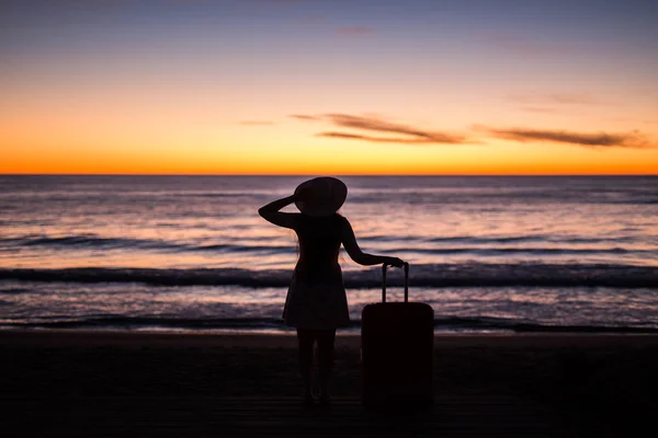 Viaggio, vacanza e concetto di viaggio estivo - silhouette di giovane donna in abito estivo e cappello in cerca di un mare — Foto Stock