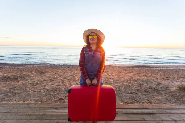 Viagens, férias e conceito de pessoas - Feliz turista mulher rindo com mala vermelha perto do mar — Fotografia de Stock