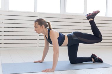 İnsanlar, spor ve fitness kavramı - ince genç kadın eşek tekme egzersiz yaparak spor giyim