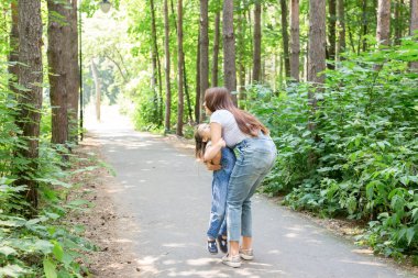 Aile, ebeveynlik ve doğa kavramı - yeşil parkta eğleniyor kızı annesiyle