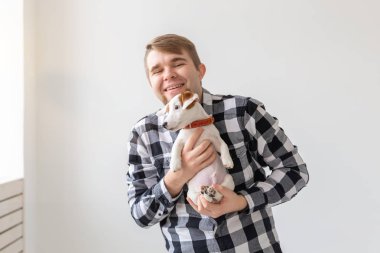 insanlar, hayvanlar ve köpekler kavramı - sarılma komik köpek yavrusu beyaz arka plan üzerinde genç adam