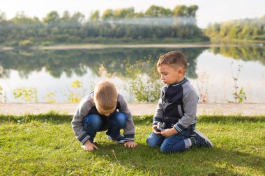 Çocuk ve doğa kavramı - çim üzerinde doğa arka plan üzerinde oturan iki kardeş