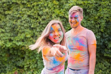 Tatil, bayram ve insanlar kavramı - mutlu çift yüzlerinde çok renkli toz ile eğleniyor